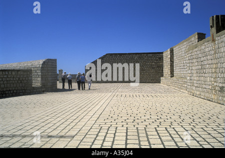 I turisti in lontananza ad esplorare il tredicesimo secolo parapetto di pietra mura che circondano Dubrovnik Croazia Dalmazia Meridionale Foto Stock