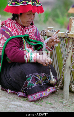 Una donna Quechua gira la lana per la tessitura in abbigliamento tradizionale nel villaggio di Amaru, nei pressi di Pisac, Perù, Sud America Foto Stock