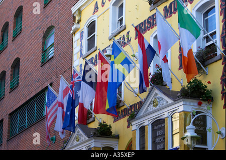 Bandiere multinazionale appeso al di fuori del tradizionale bar irlandese di Temple Bar a Dublino accanto al moderno edificio di mattoni rossi Foto Stock
