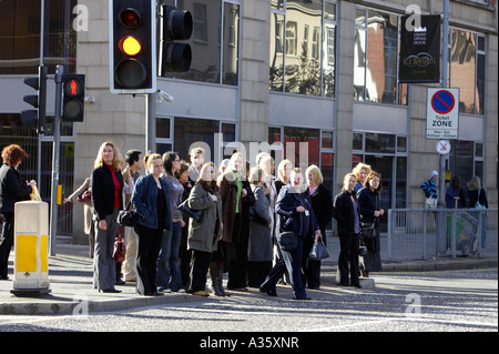 La folla di persone in attesa sul cambiamento di luce di attraversare la strada al semaforo in un centro della città Foto Stock