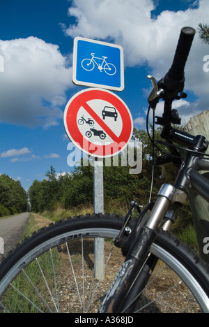 Bicicletta parcheggiata contro un cartello stradale post su una via che passa attraverso la foresta di Landes Francia Aquitania Foto Stock