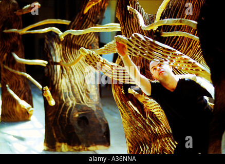 Scultore riciclato con figure in legno di quercia intagliato da lui con una sega a nastro Foto Stock