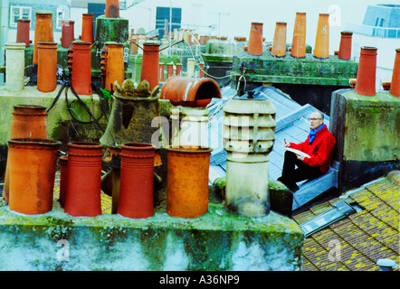 Sul tetto di un artista disegna un paesaggio urbano tra le lastre di ardesia e piastrelle. Foto Stock
