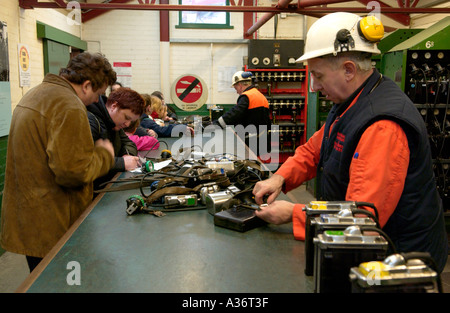 Ex minatori lavorando come guide con i visitatori nella sala lampade a Big Pit National Coal Museum Blaenavon South Wales UK Foto Stock