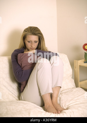 Giovane donna che guarda depressa seduta su un divano, inglese britannico donna - coronovirus, covid19 covid-19 virus, virus, Inghilterra, Gran Bretagna, Regno Unito Foto Stock