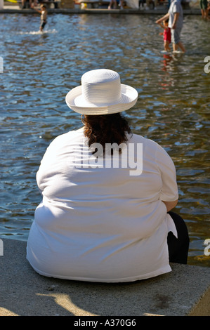 Anonimo il sovrappeso donna seduta su un gradino in prossimità di acqua. Foto Stock