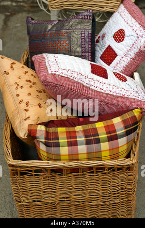 Cucito a mano pillows accatastati in un tessuto di vimini cesto. Foto Stock