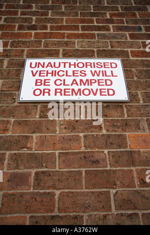 Veicoli non autorizzati sarà bloccato o rimosso segno su un muro di mattoni Foto Stock