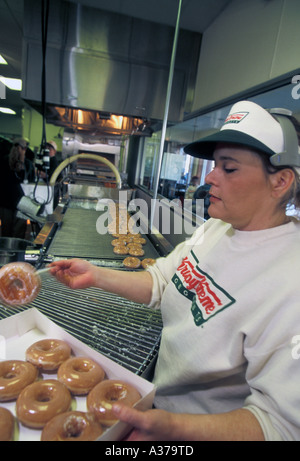 Warren Michigan un lavoratore le scatole fino appena fatte le ciambelle a Krispy Kreme donut shop Foto Stock