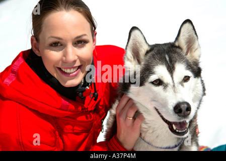 Frau im Winter mit hund, giovane donna in rosso vestito di sci con un cane Husky nella neve Foto Stock