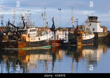 Barche da pesca scozzesi; navi e riflessi astratti al porto di Fraserburgh illuminato dal sole tramontare, Scozia Regno Unito Foto Stock