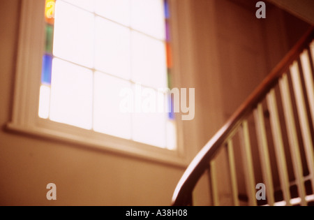 Finestra Defocussed con chiare e vetrate colorate e bannister rotaie su scala lo sbarco di periodo house Foto Stock