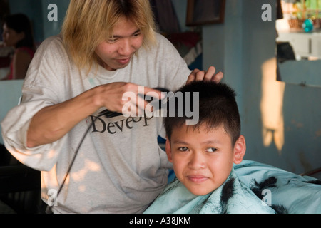 Barbiere il taglio di un giovane ragazzo s capelli in Thanh da area di Saigon Foto Stock