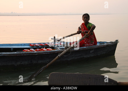 Donna vendita candela galleggiante e fiore offerte da la sua barca sul fiume santo Ganges, Varanasi, Uttar Pradesh, India Foto Stock