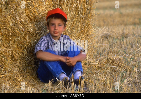 Giovane ragazzo in rilassante hayfield Foto Stock