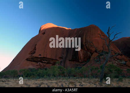 Ayers Rock poco dopo l'alba come visto lungo la base a piedi intorno a Uluru punta superiore illumina illumina Foto Stock