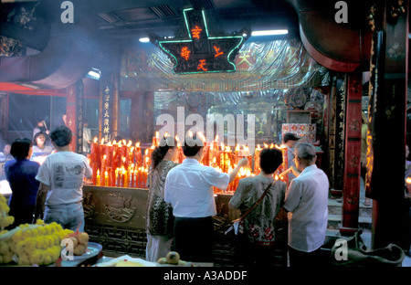 Interno del Sanjao Pho Sua tempio Cinese aka Padre Tiger tempio, con gli adoratori rosso illuminazione candele di cera, Thanon Tanao, Bangkok, Thailandia Foto Stock