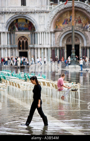 Italia Veneto Venezia Aqua Alta Alta allagamenti Piazza San Marco a piedi nudi artisti seduto con i piedi in acqua basilica di verniciatura Foto Stock