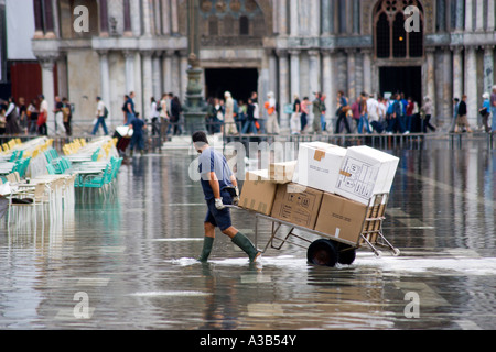 Italia Veneto Venezia Piazza San Marco Aqua Alta acqua alta erogazione di allagamento uomo tirando il carrello caricato attraverso l acqua in piazza Foto Stock