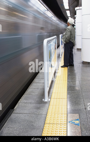 Uomo in piedi sulla piattaforma della metropolitana Foto Stock