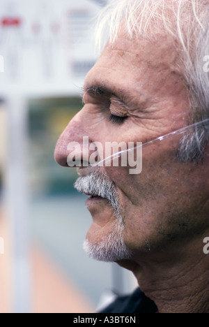 Uomo anziano che soffre di una malattia polmonare indossa una maschera ad ossigeno come egli esercita presso un club della salute. Foto Stock