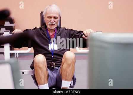 Uomo anziano che soffre di una malattia polmonare indossa una maschera ad ossigeno come egli esercita presso un club della salute. Foto Stock