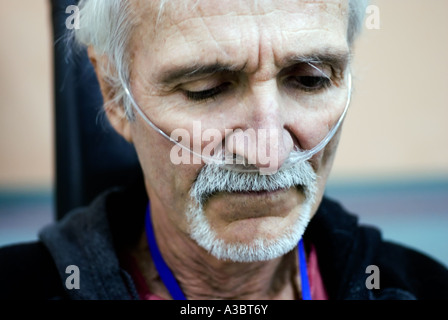 Uomo anziano che soffre di una malattia polmonare indossa una maschera ad ossigeno come egli esercita presso un club della salute. Foto Stock