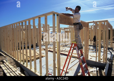 Operaio edile in piedi su una scala a lavorare sul telaio di una casa residenziale in Albuquerque NM Foto Stock
