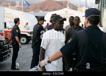 Polizia spagnola nella prevenzione di malattia guanti protettivi e maschere escort immigrati clandestini provenienti dal nord africa appena arrivato in barca los christianos Foto Stock