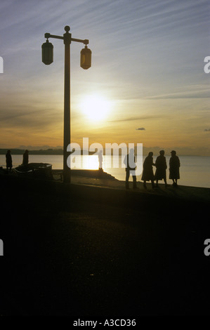 Persone in silhouette camminando lungo il lungomare di Sidmouth in inverno, Devon, Inghilterra Foto Stock