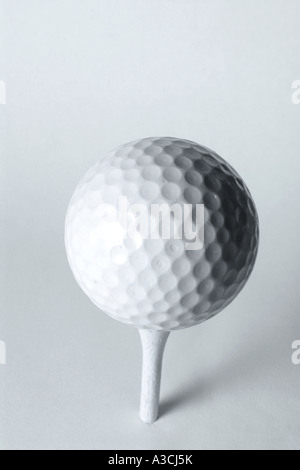 White pallina da golf su bianco tee di legno peg sfondo semplice Foto Stock