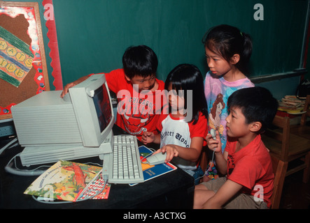 I bambini lavorano insieme a un computer presso una scuola elementare nel quartiere di Chinatown di New York City Foto Stock