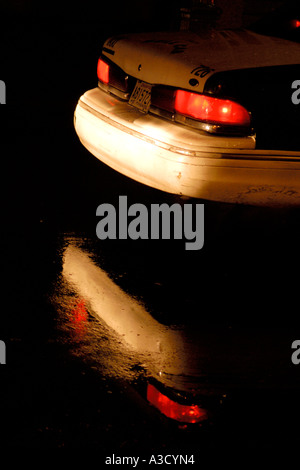 La parte posteriore di un American automobile della polizia si riflette in una pozza su un molto umido sera a New Orleans Foto Stock