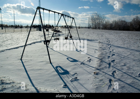 Un swingset inutilizzati nel parco giochi dell'inverno Foto Stock