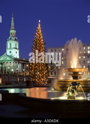 Funzione di acqua in Trafalgar Square Londra Inghilterra REGNO UNITO & albero di Natale luci con proiettori su fontane & St Martin nei campi chiesa & guglia Foto Stock