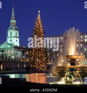 Funzione di acqua in Trafalgar Square Londra Inghilterra REGNO UNITO & albero di Natale luci con proiettori su fontane & St Martin nei campi chiesa & guglia Foto Stock