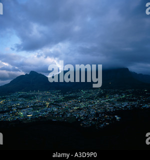 Vista sulla città di Cape Town accesa dopo il tramonto e bassa pioggia nuvole sulla Table Mountain in Sud Africa Foto Stock