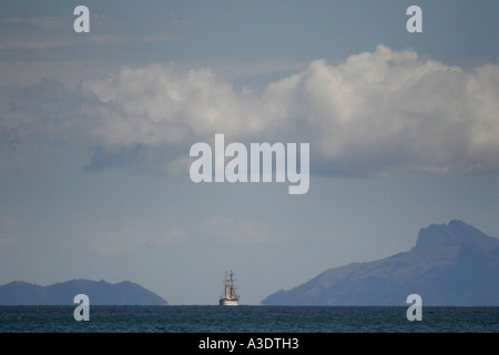 Due-masted yacht su orizzonte, isole distanti su entrambi i lati, il bianco delle nuvole sopra, visto attraverso la distanza haze, Isole Figi Foto Stock