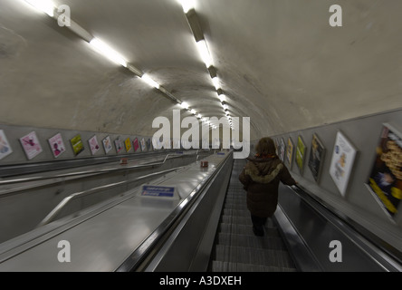 Donna sulla metropolitana di Londra escalator Foto Stock