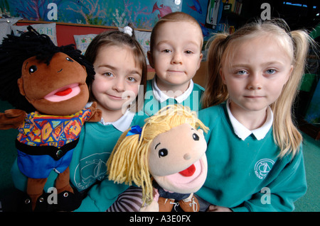 2 ragazze e un ragazzo in uniformi di scuola con fantoccio bambole in aula Foto Stock