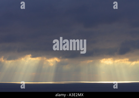 Tempestose nuvole scure con sole splendente sole che splende sul mare Foto Stock