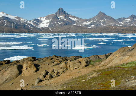 Confezione di ghiaccio e iceberg di fronte montagne dalle vette innevate fiordo Ammassalik Eastgreenland Foto Stock