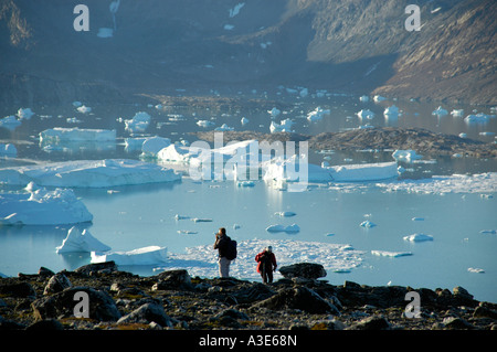 Persone nella parte anteriore del fiordo con iceberg e montagne Nagtivit Kangertivat Fjord Eastgreenland Foto Stock