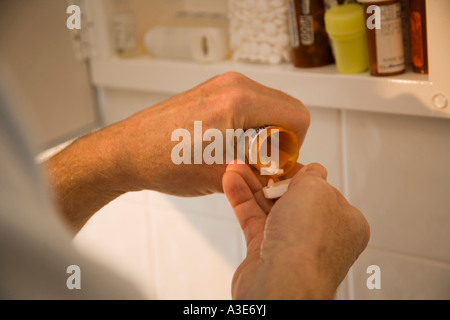 Senior uomo che parla di farmaci dal suo armadio medicina. Foto Stock