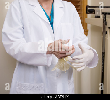 Medico di mettere dei guanti di protezione in lattice su prima di un esame. Foto Stock