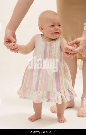 Gli otto mesi Baby girl ad imparare a camminare con l'aiuto di sua madre. Foto Stock