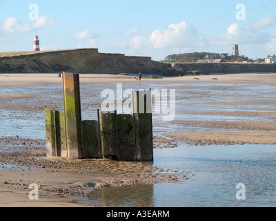 Faro e il campanile di una chiesa con danneggiato le difese del mare con la bassa marea, happisburgh, norfolk, Est Anglia, Regno Unito Foto Stock