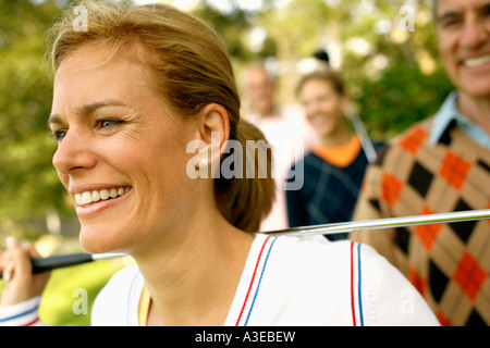 Close-up di una metà donna adulta tenendo un golf club e sorridente Foto Stock