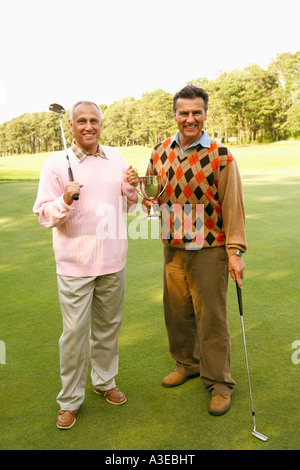 Ritratto di due uomini maturi tenendo un trofeo e golf club Foto Stock