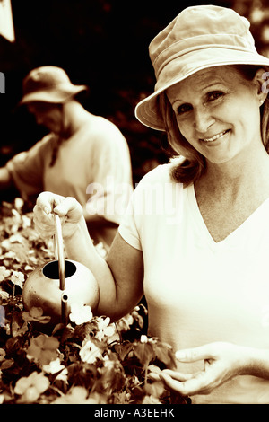 Ritratto di una donna matura, impianti di irrigazione con un uomo maturo in background Foto Stock